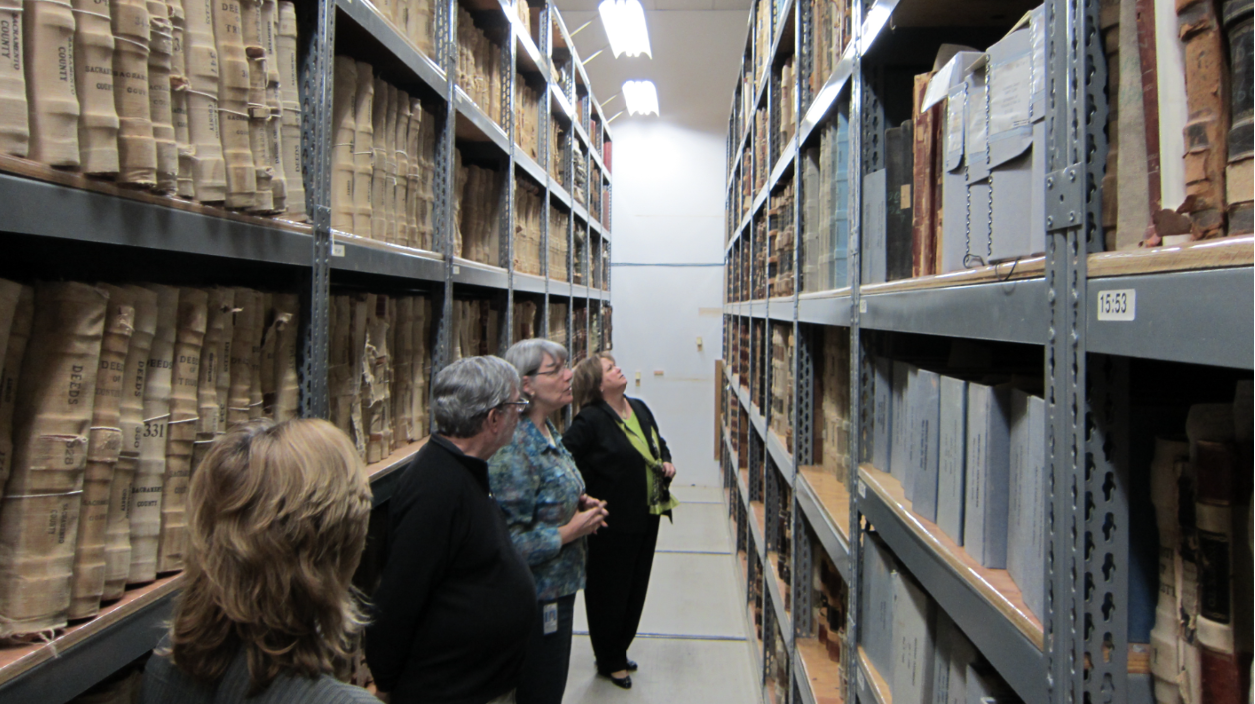A group of folks looking at CSH's vault shelving with volumes on them