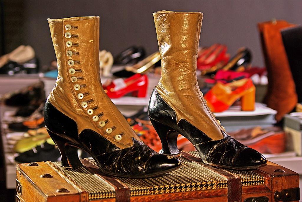 A pair of brown and black shoes sitting on a chest in front of other pairs of shoes