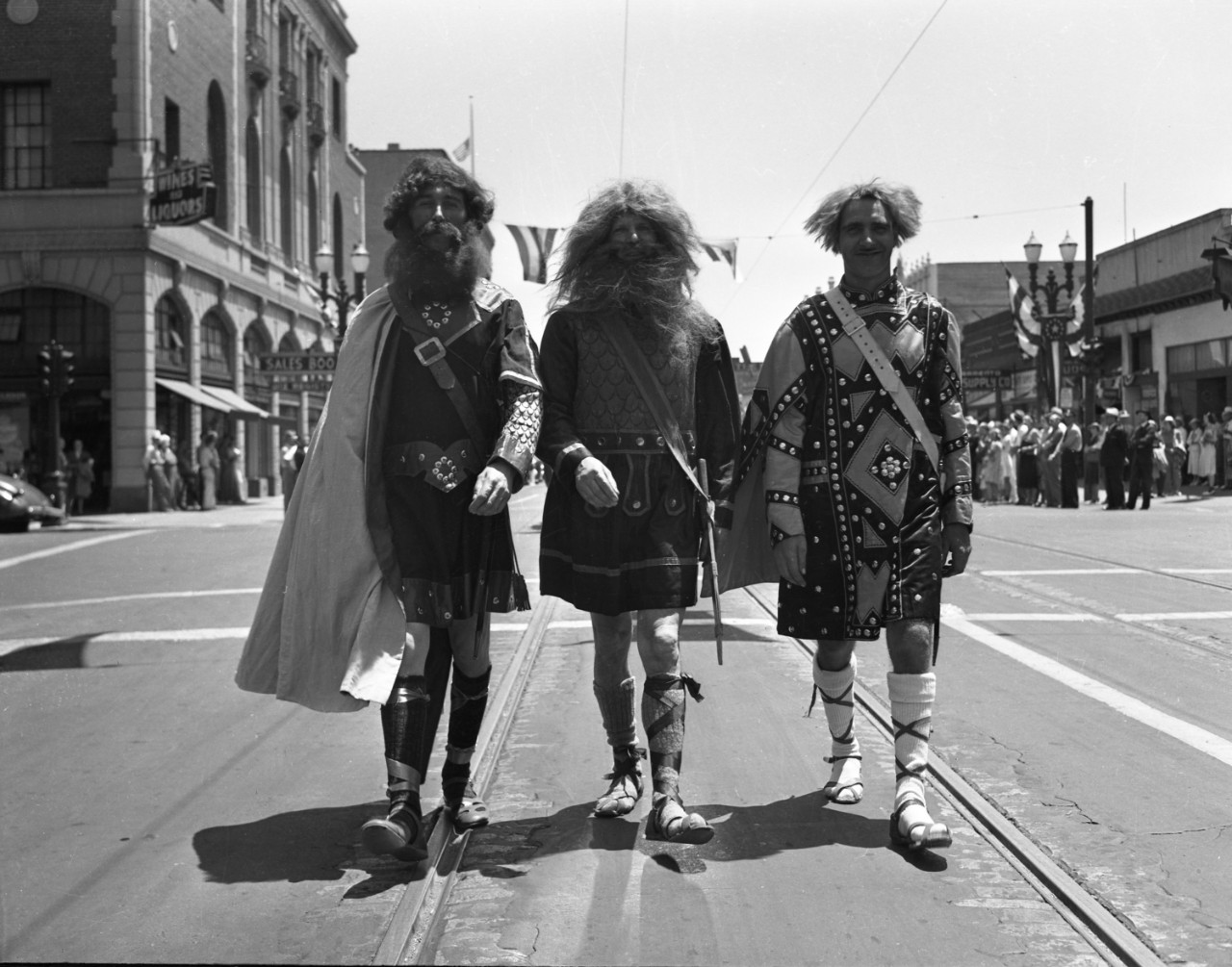 Black and white photo of three men walking down the street in Viking costumes.