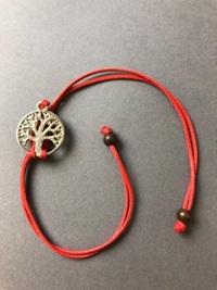 A red string bracelet with a silver metal tree pendant