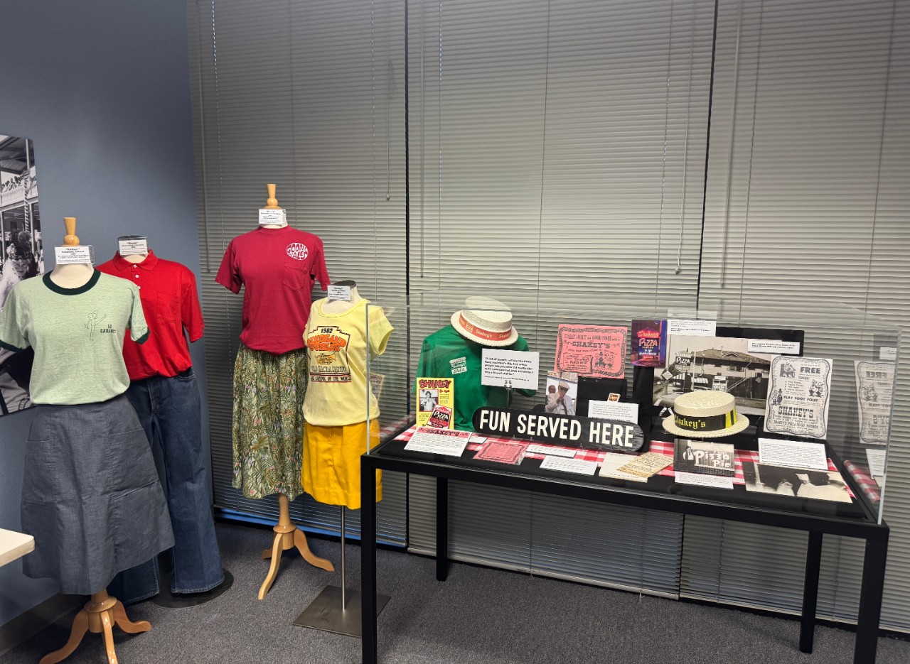 Display case with clothing dummies next to it