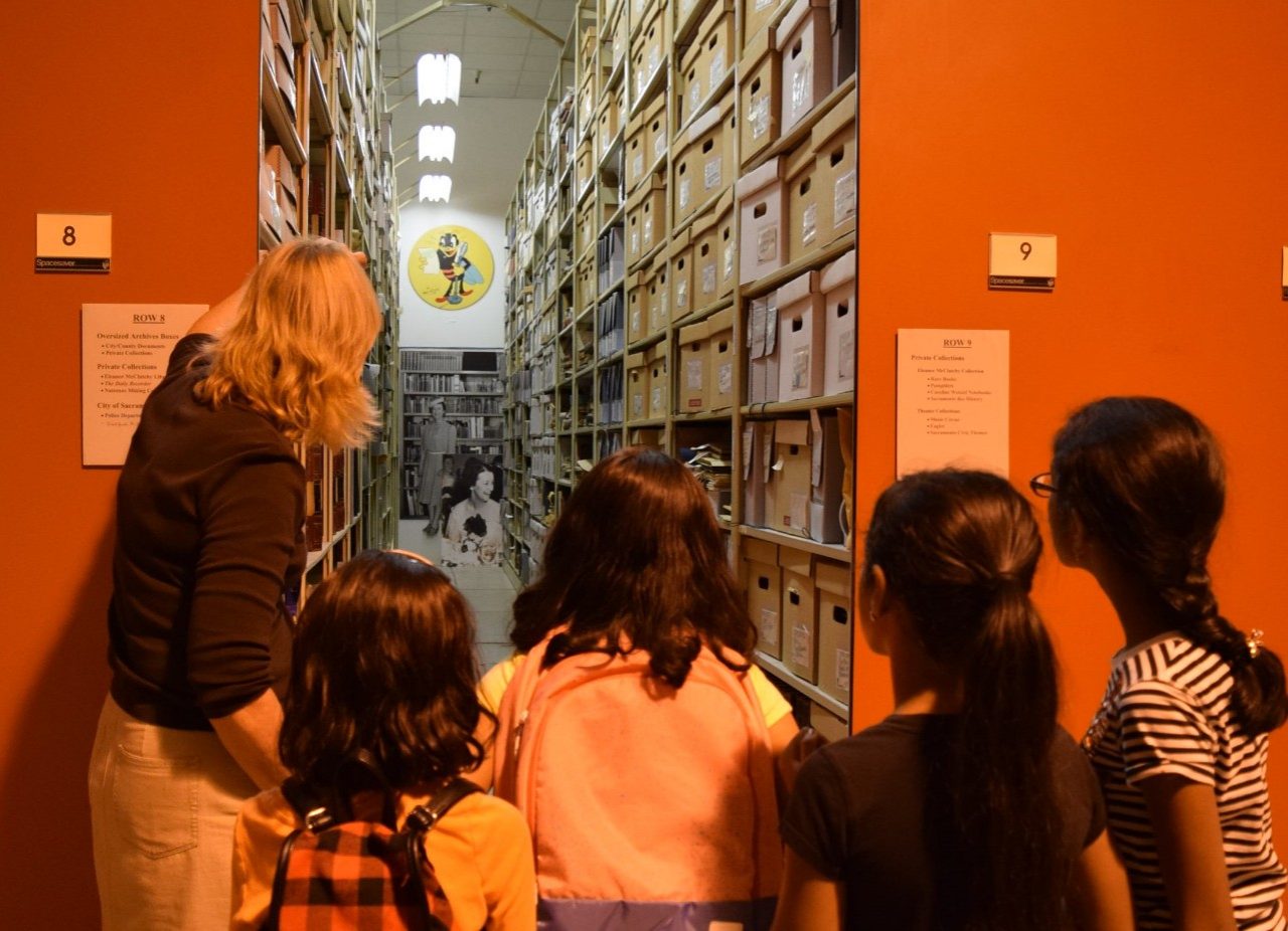 A CSH employee gives a tour of an aisle with boxes to four children.